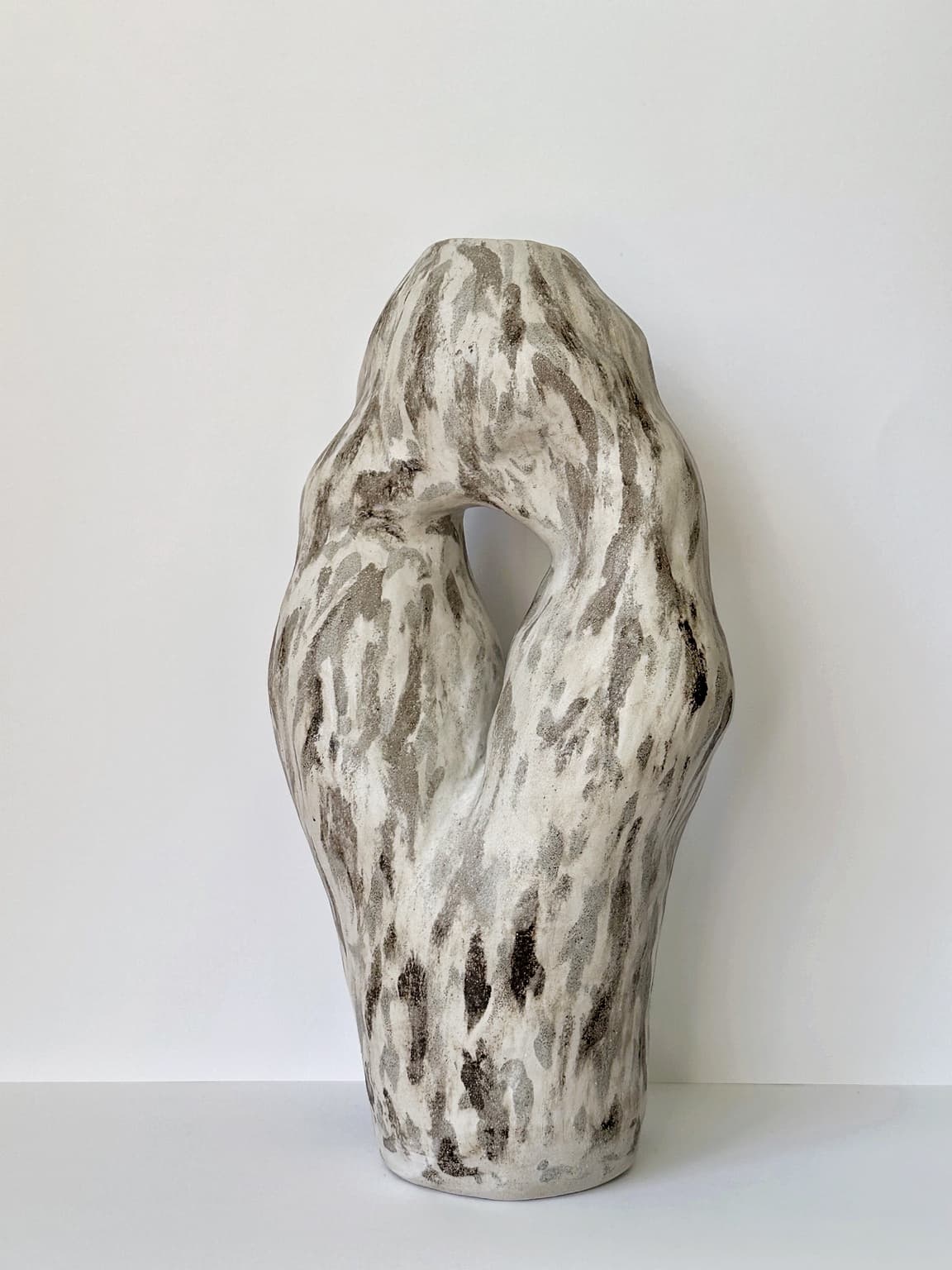 A tall CLÆY loop vessel, marbled in cream, grey and iron brown