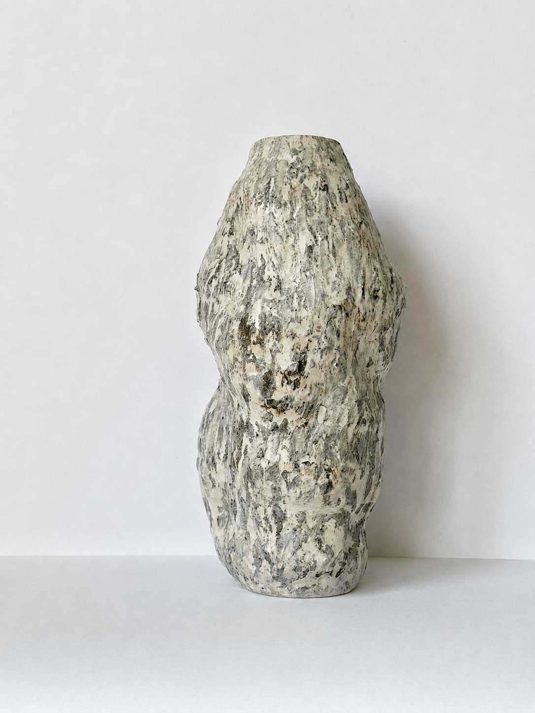 A tall cream and grey CLÆY vase with a richly textured surface